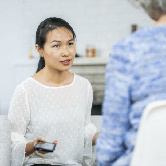 woman with mobile phone talking with another person