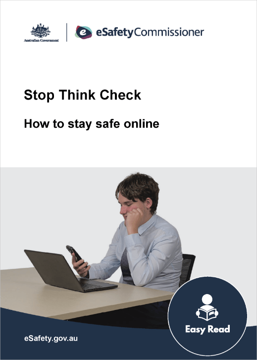 Young man sitting at a desk head on his hand looking at a mobile phone and a laptop screen